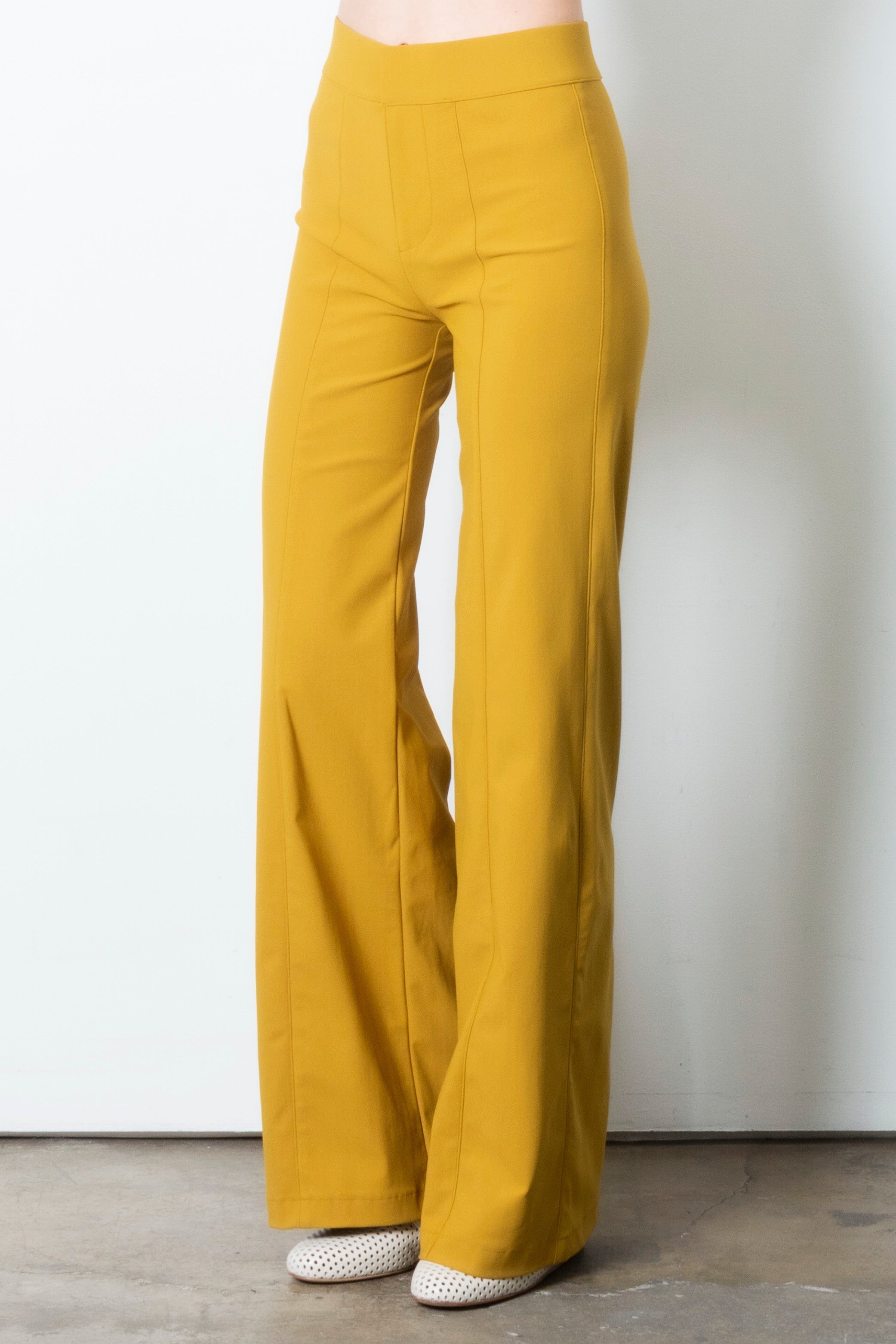 Mustard yellow wide leg pants on a plain background