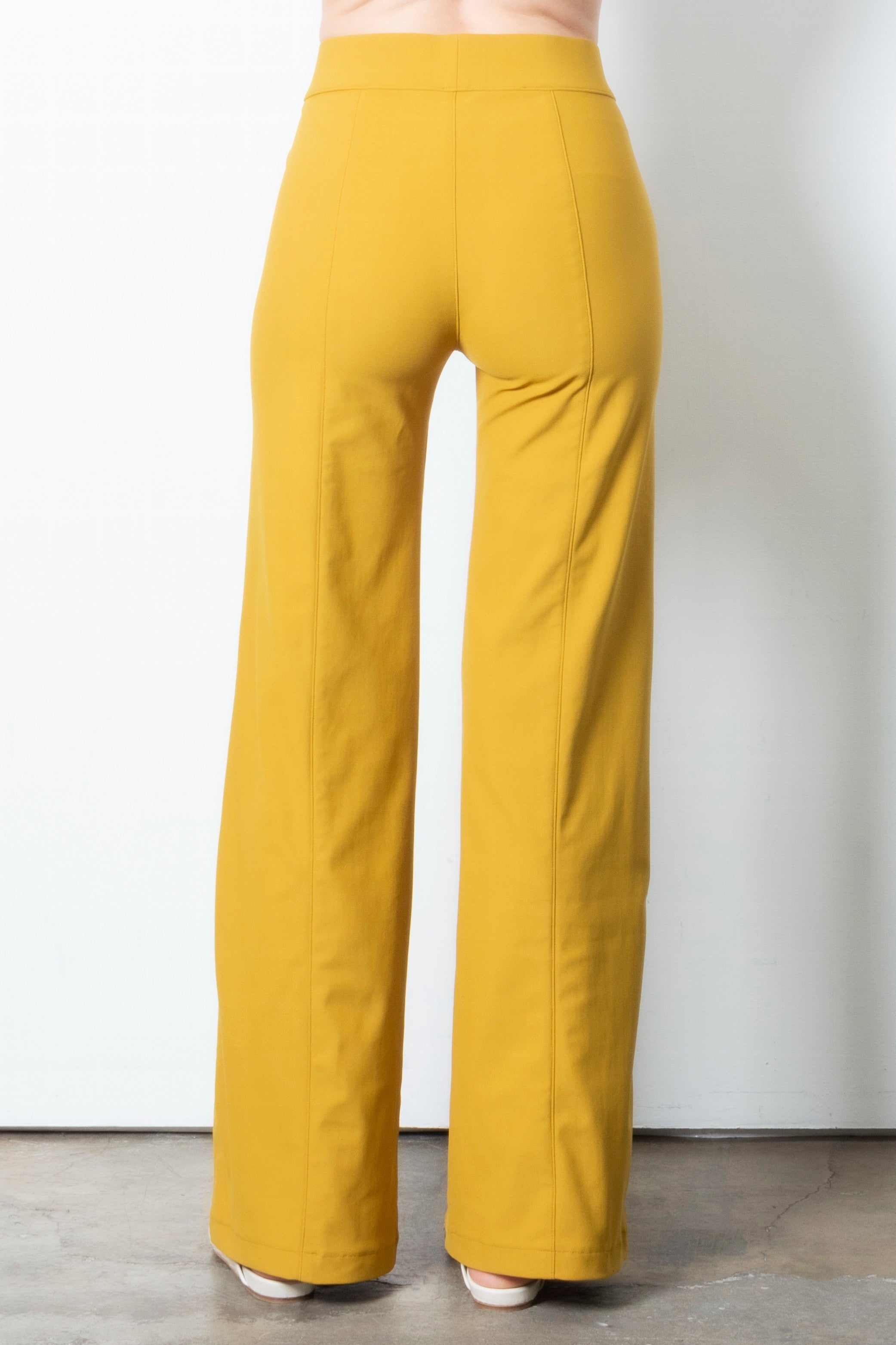 Mustard yellow wide leg pants on a plain background