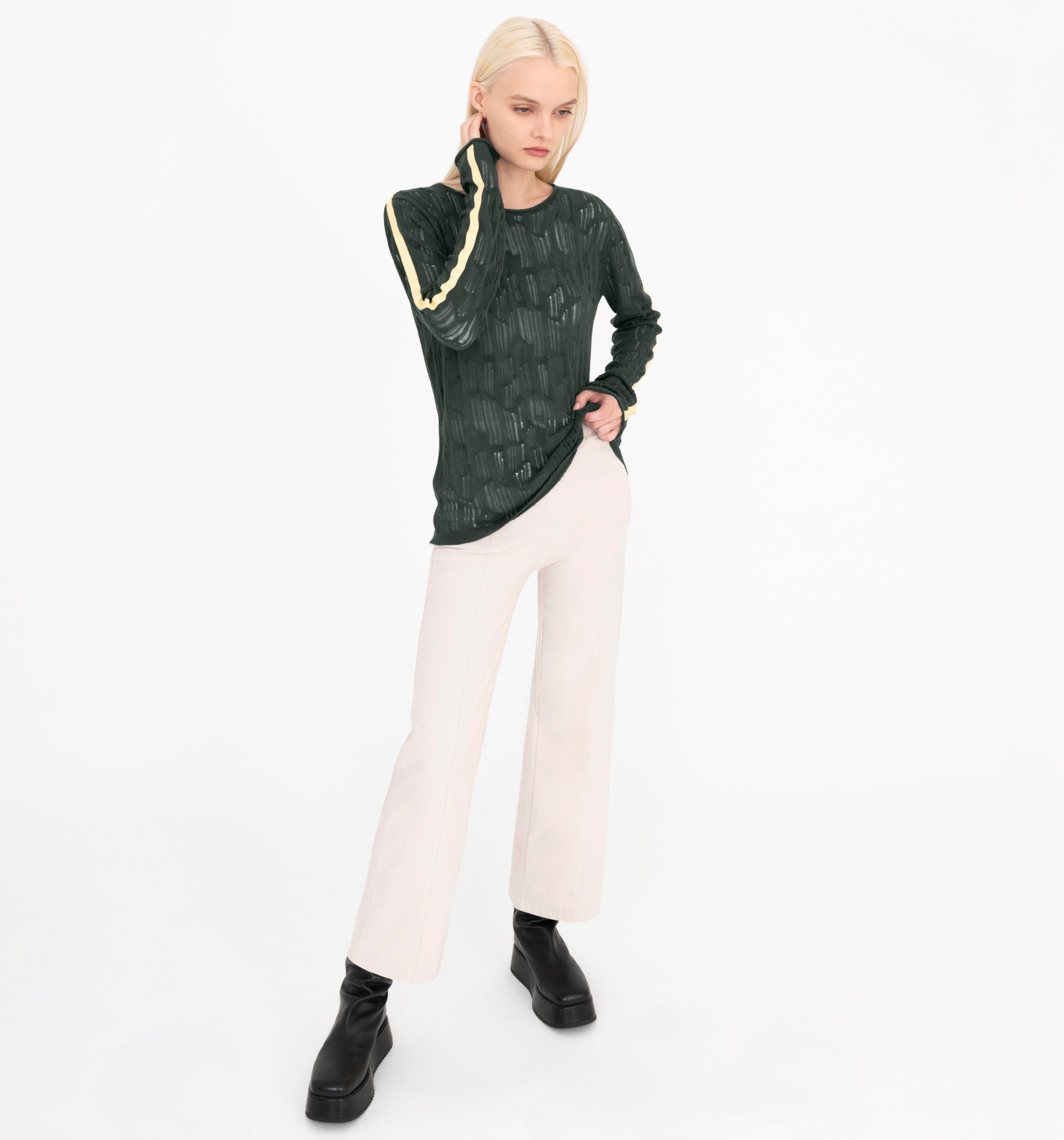 Person wearing a green top and beige pants on a white background