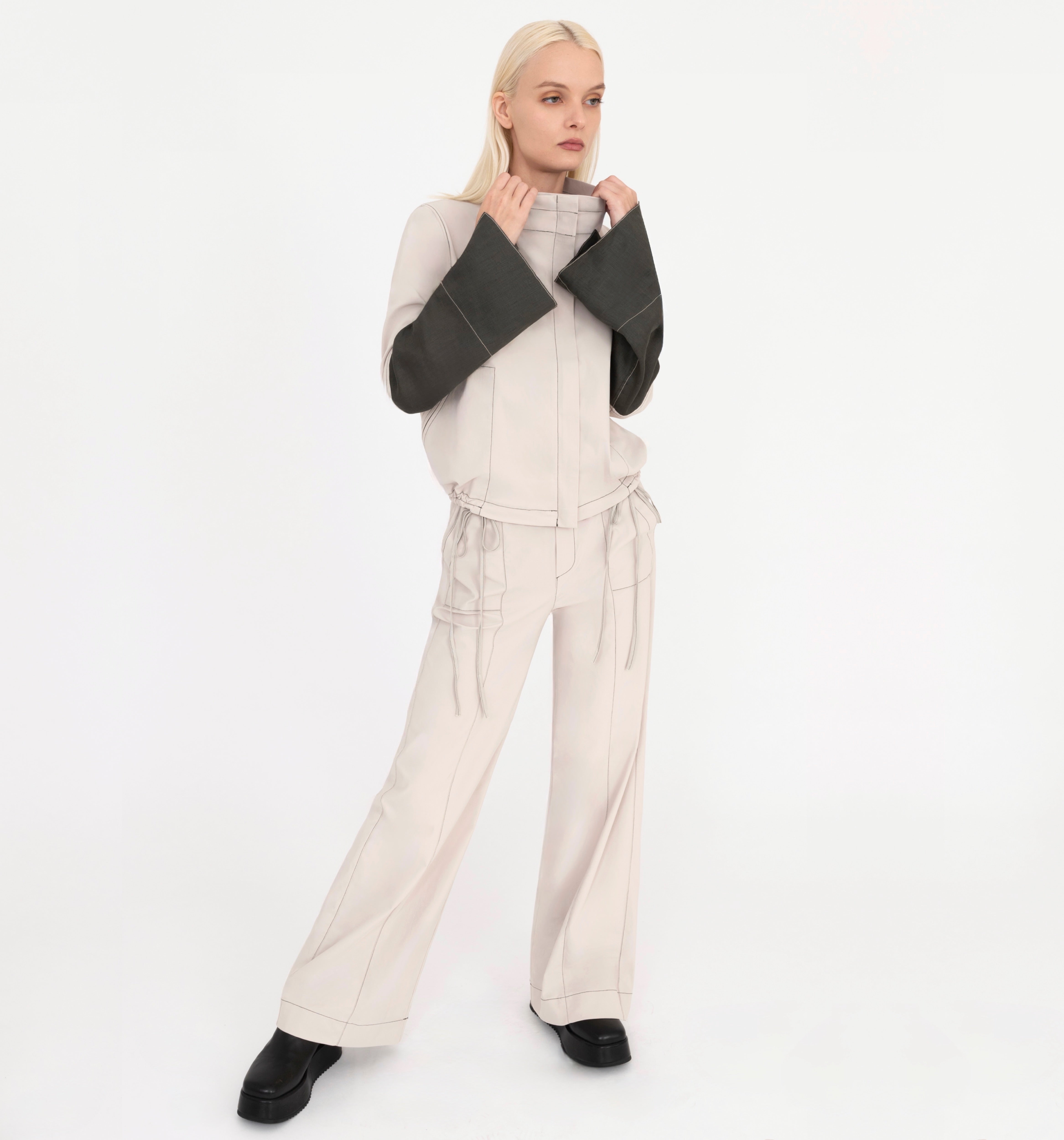 Woman wearing a beige jacket and pants on a white background