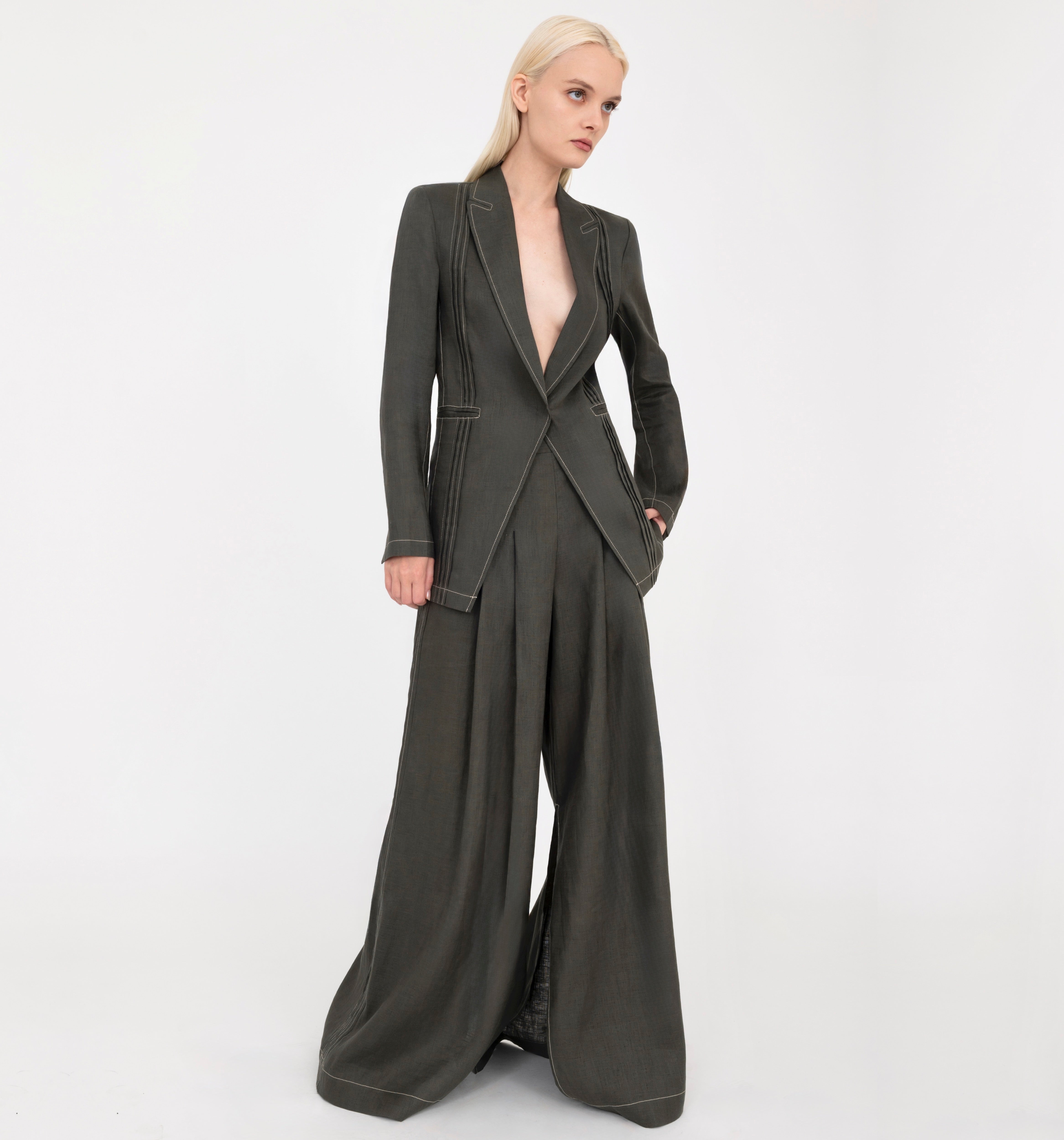 Woman wearing a green blazer and wide-leg pants on a white background