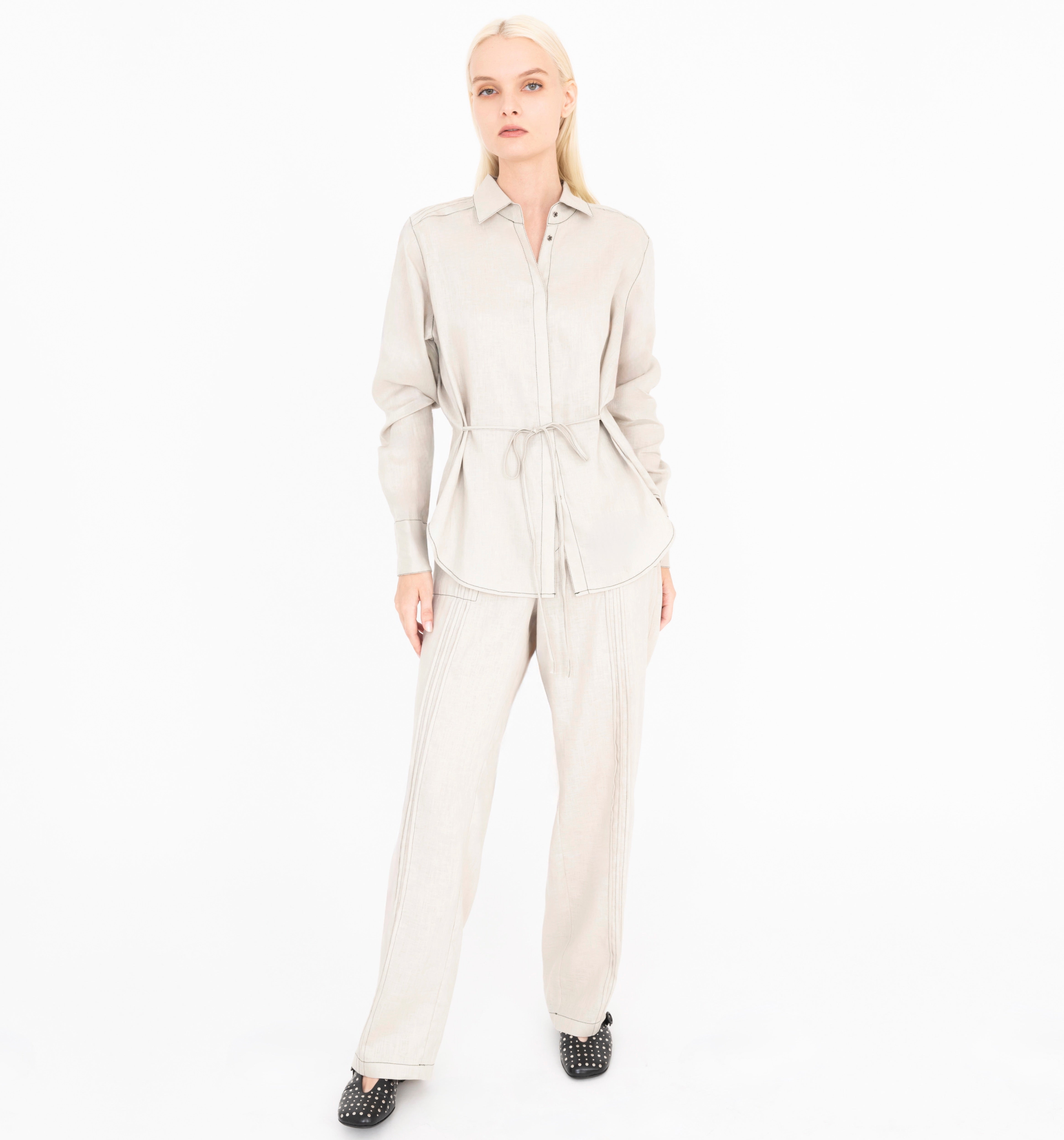 Woman wearing a beige shirt and pants on a white background