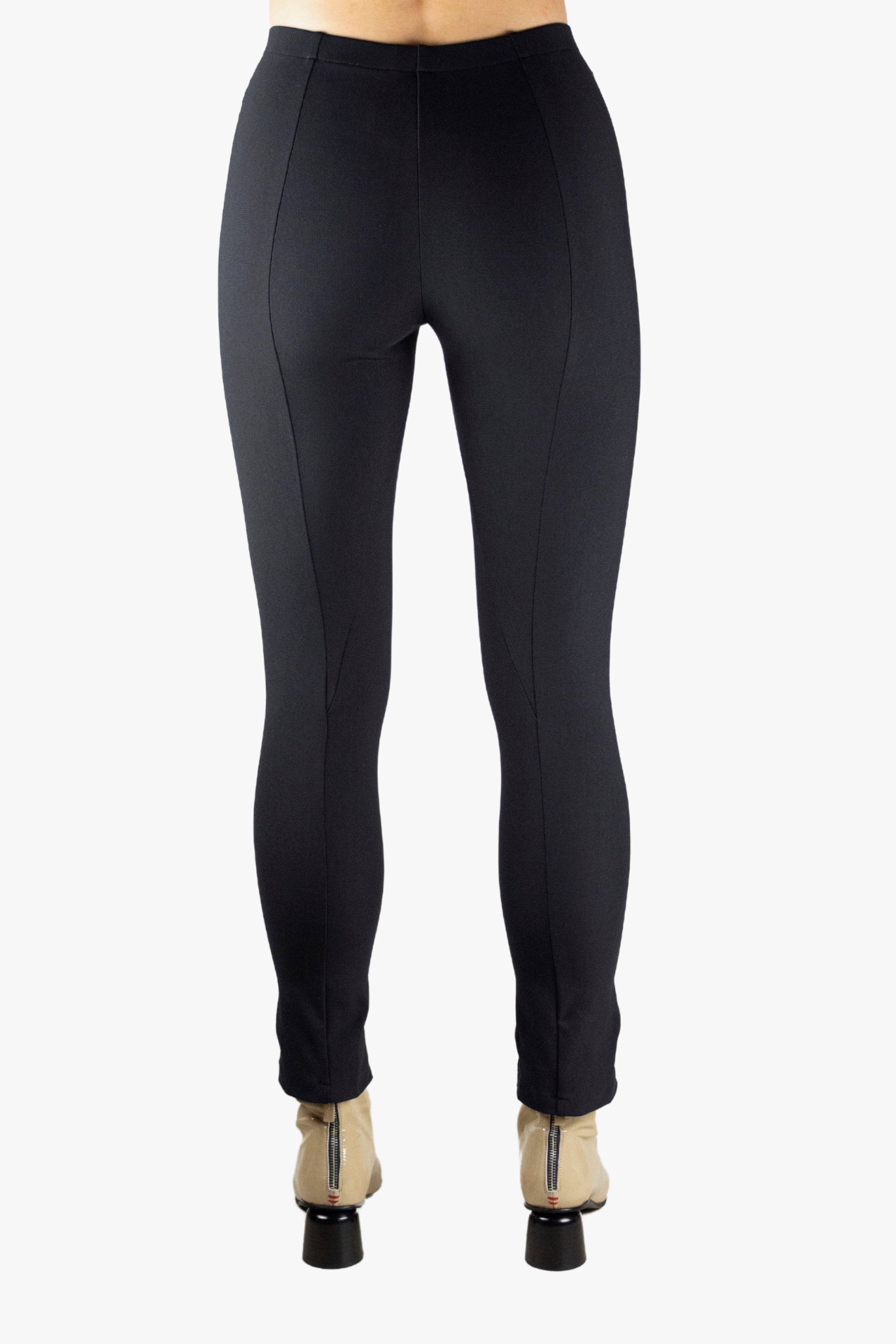 Person wearing black leggings with a slit on a plain background