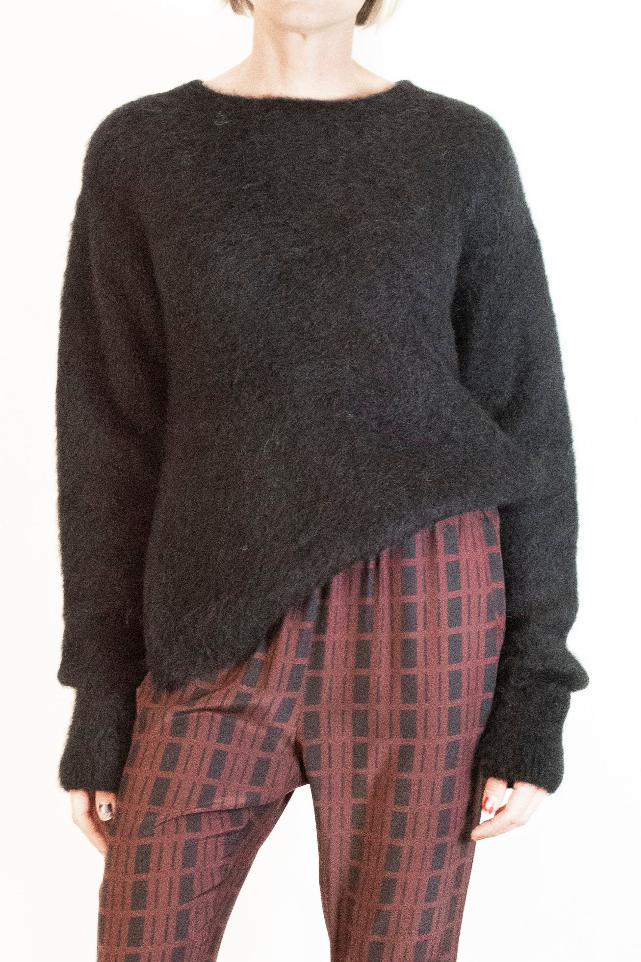 Person wearing a dark sweater and plaid pants on a white background