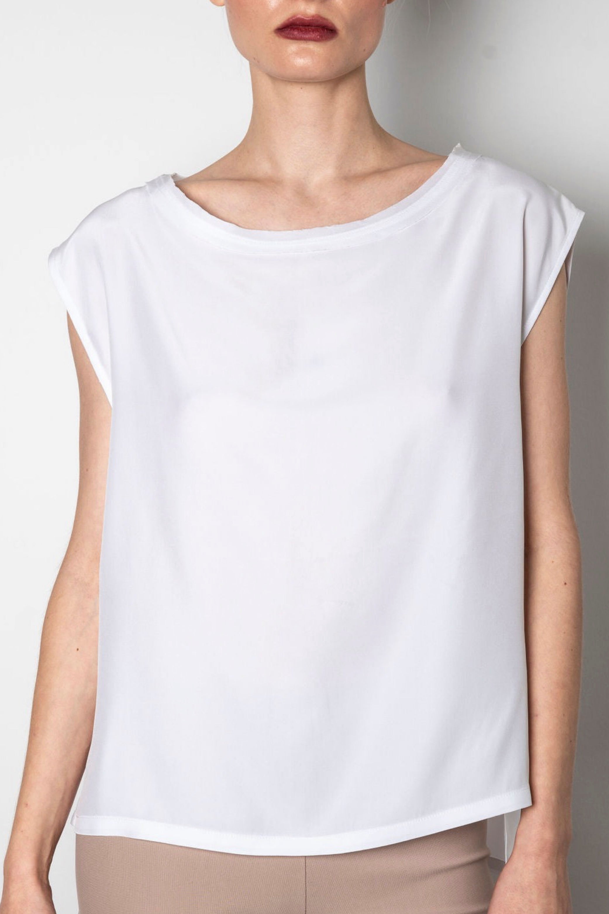 White sleeveless top worn by a person against a plain background
