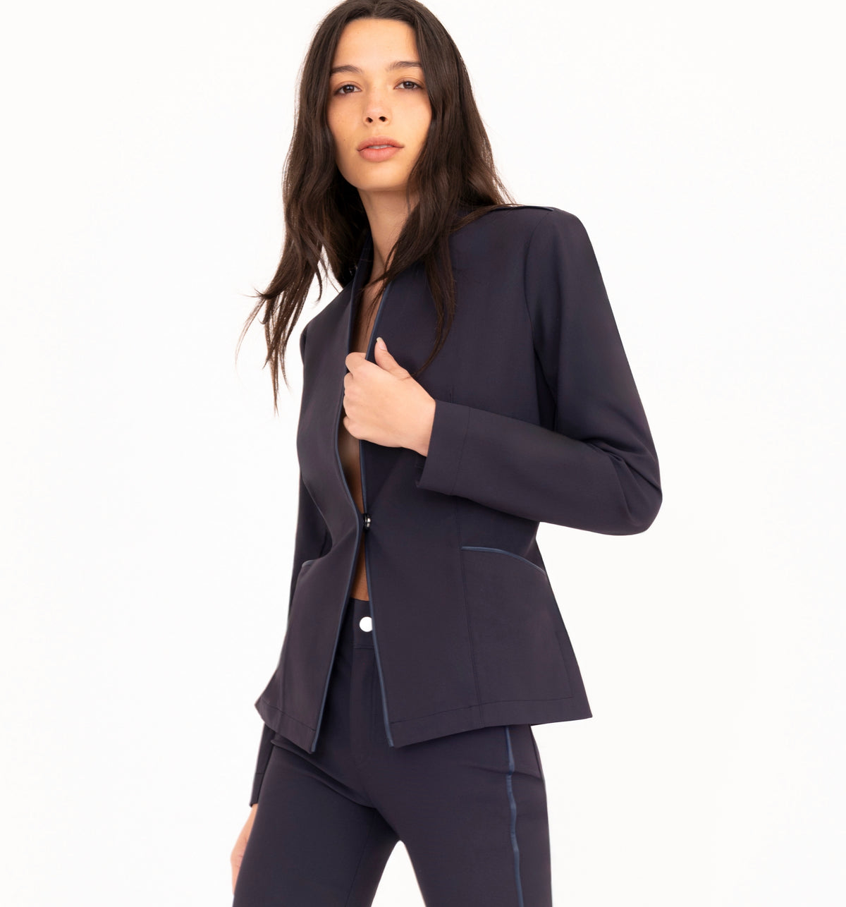 A woman modeling a dark navy blue tech-stretch blazer and matching pants against a clean white background