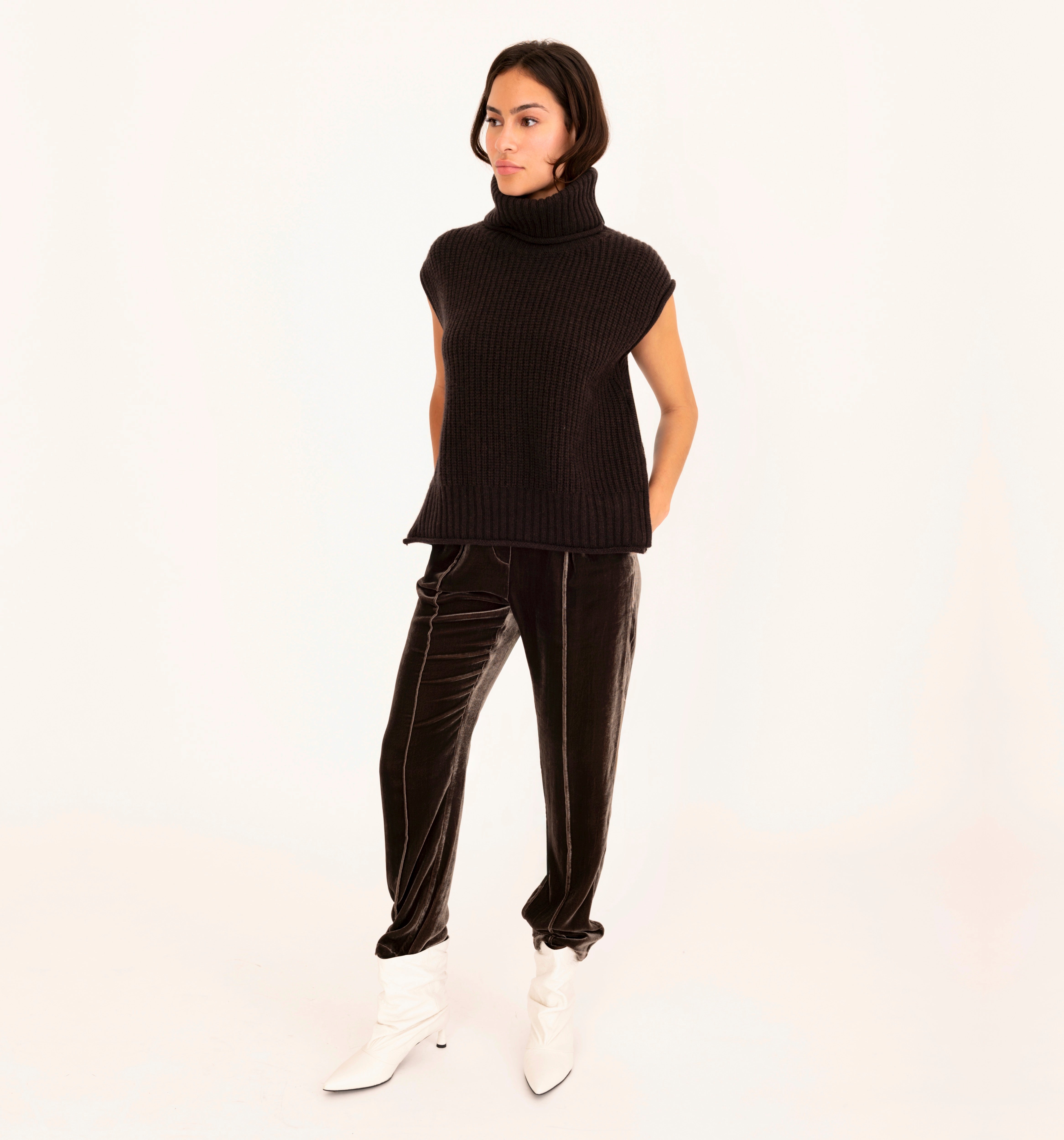 Woman wearing a brown sleeveless top and velvet pants on a white background